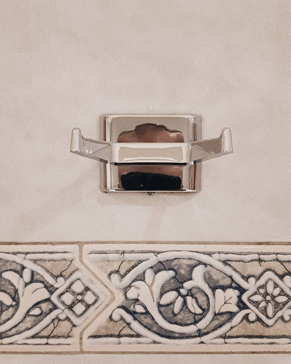 A double hook made of metal, chrome, fixed to a wall. Found on a restaurant in Mexico City, Mexico, 2019.