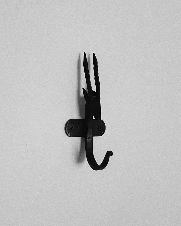A single hook made of metal, oxide, screwed to a wall. Found on a private home in Malinalco, Mexico, 2020.