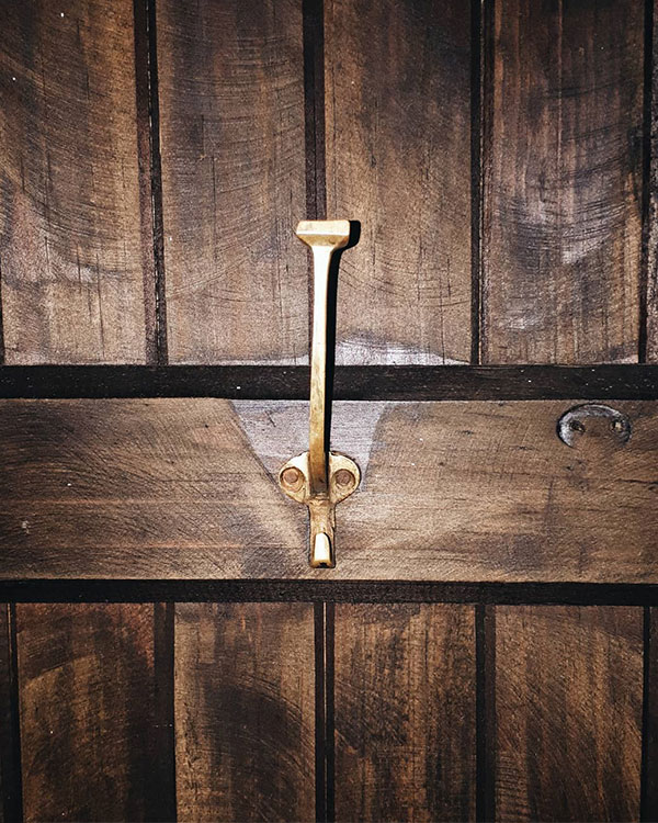 A double hook made of metal, brass, nailed to a door. Found on a private home in Valle de Bravo, Mexico, 2020.