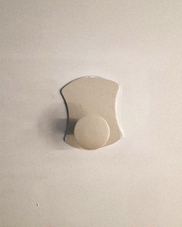 A single hook made of beige plastic, fixed to a door. Found on a private home in Lyon, France, 2020.