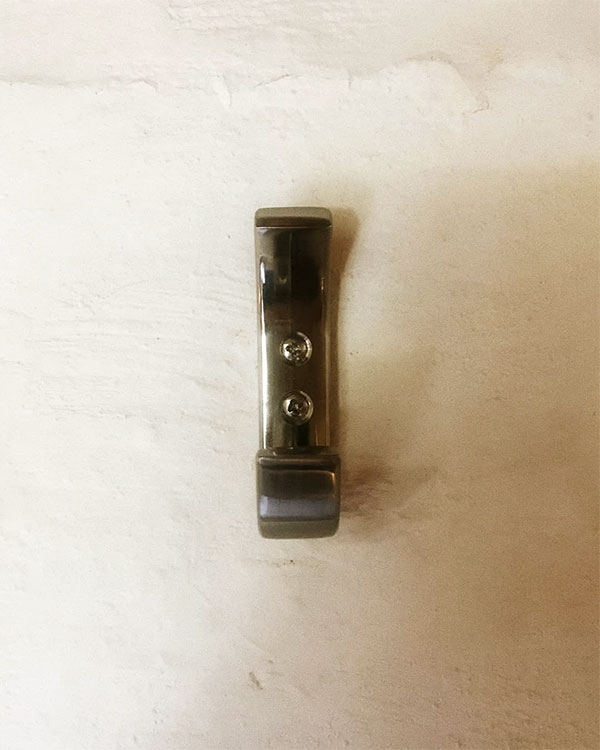 A double hook made of metal, brass, screwed to a wall. Found on a private home in Malinalco, Mexico, 2021.