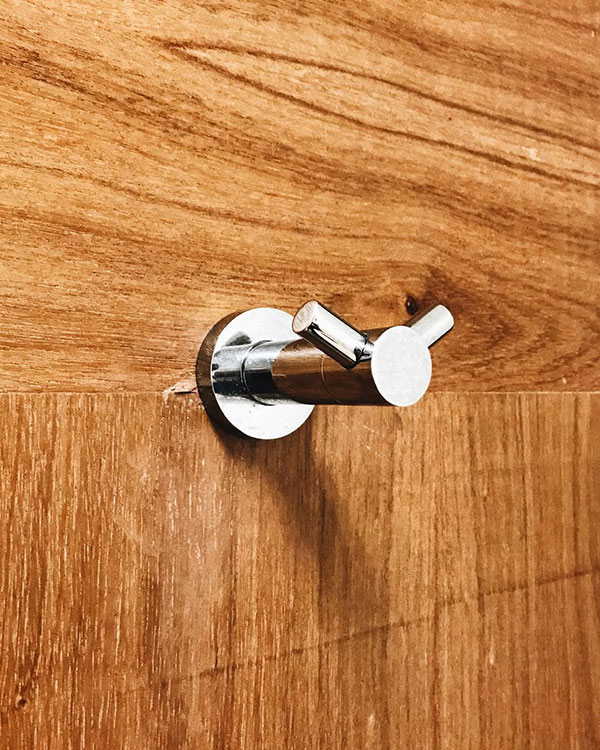 A double hook made of metal, chrome, fixed to a door. Found on a hospital in Mexico City, Mexico, 2022.