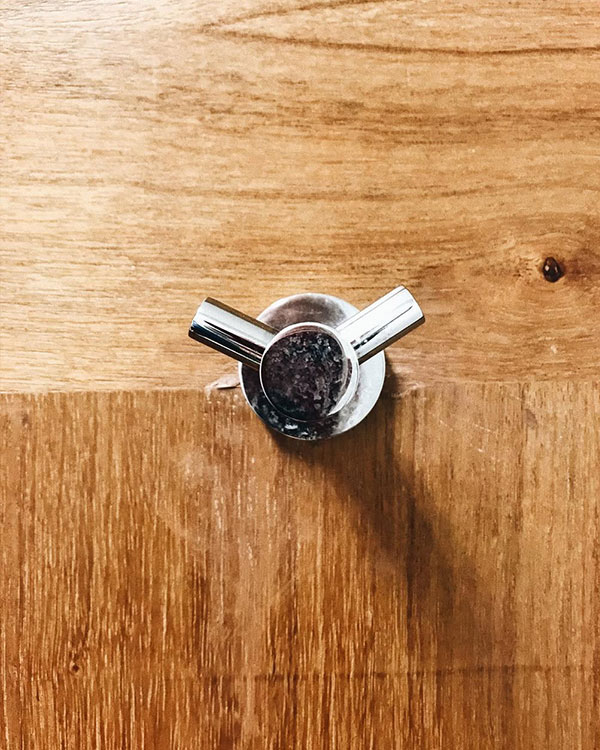 A double hook made of metal, chrome, fixed to a door. Found on a hospital in Mexico City, Mexico, 2022.