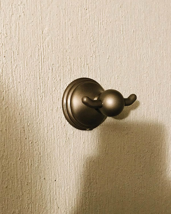 A double hook made of metal, brass, fixed to a wall. Found on a private home in Aguascalientes, Mexico, 2022.