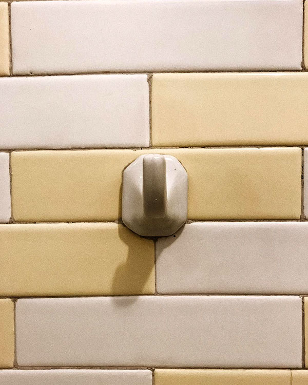 A single hook made of stoneware, white enamel, fixed to a wall. Found on a private home in Aguascalientes, Mexico, 2022.