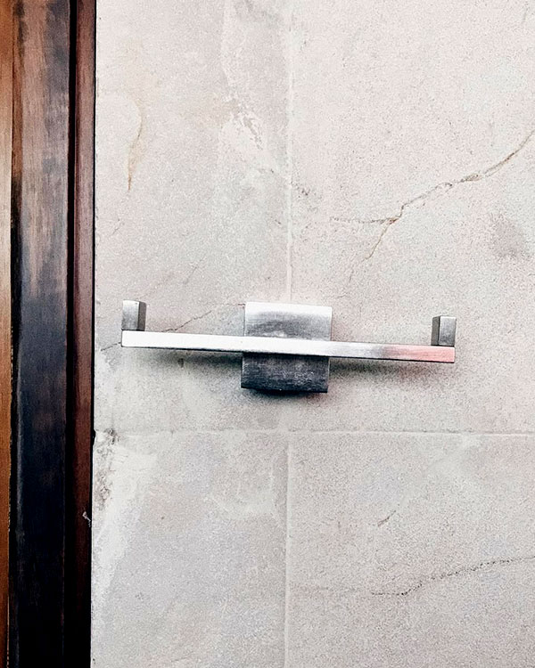 A double hook made of metal, nickel, fixed to a wall. Found on a private home in Tepoztlan, Mexico, 2022.