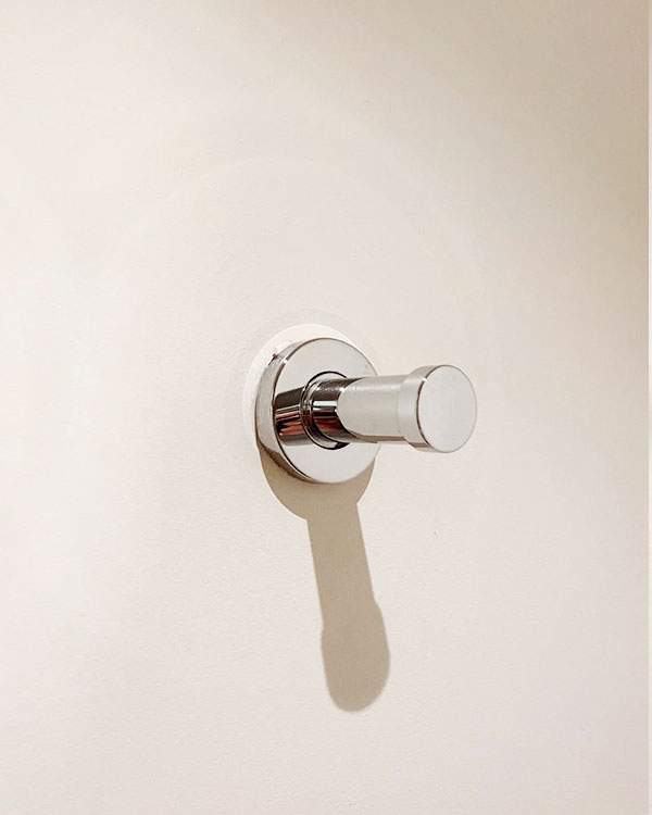 A single hook made of metal, chrome, fixed to a wall. Found on a hotel in Carcassonne, France, 2022.