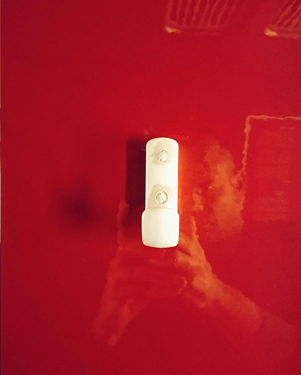 A single hook made of ivory plastic, screwed to a wall. Found on a train near Amsterdam, Netherlands, 2023.