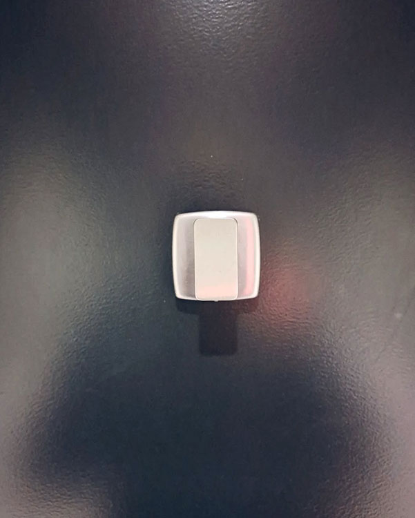 A single hook made of metal, nickel, fixed to a door. Found on a museum in Montreal, Canada, 2024.