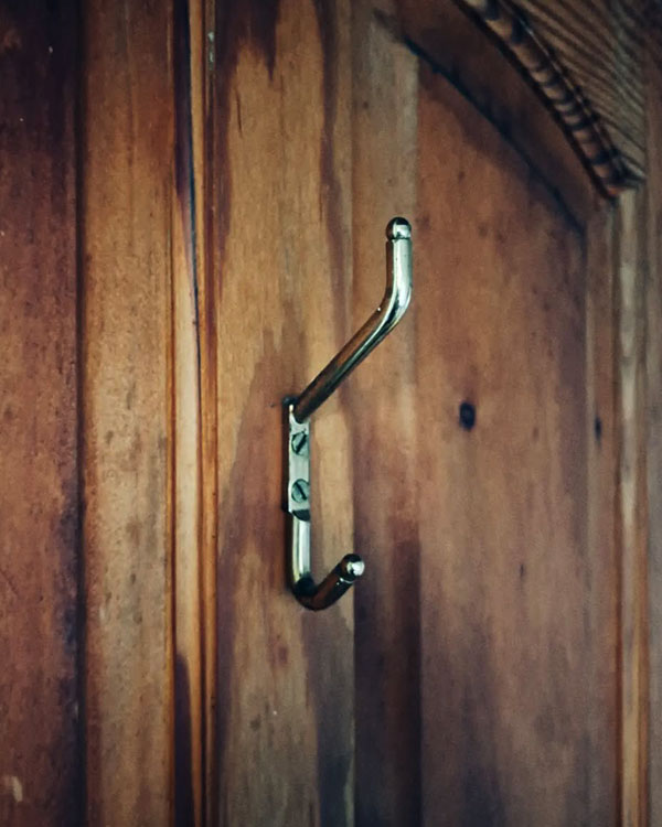 A double hook made of metal, brass, screwed to a door. Found on a private home in Malinalco, Mexico, 2024.