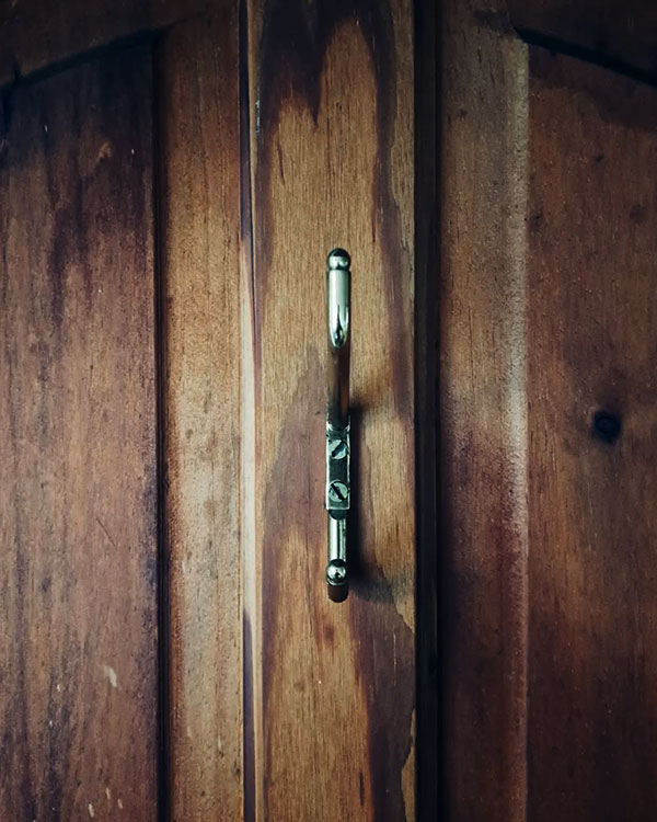 A double hook made of metal, brass, screwed to a door. Found on a private home in Malinalco, Mexico, 2024.