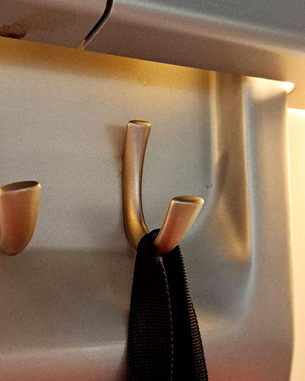 A single hook made of metal, nickel, fixed to a wall. Found on a train near Madrid, Spain, 2024.