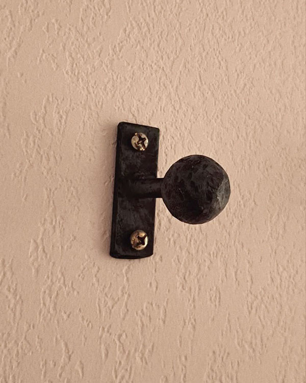 A single hook made of metal, oxide, screwed to a wall. Found on a hotel in Avignon, France, 2024.