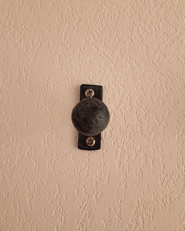 A single hook made of metal, oxide, screwed to a wall. Found on a hotel in Avignon, France, 2024.