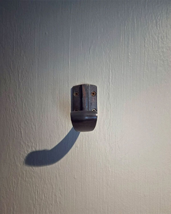 A single hook made of metal, oxide, screwed to a door. Found on a restaurant in Paris, France, 2024.