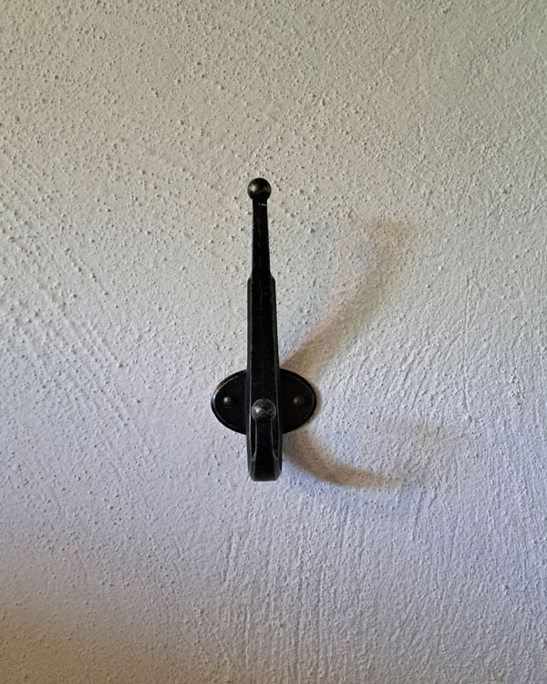 A double hook made of metal, oxide, nailed to a wall. Found on a private home in Tepoztlan, Mexico, 2025.