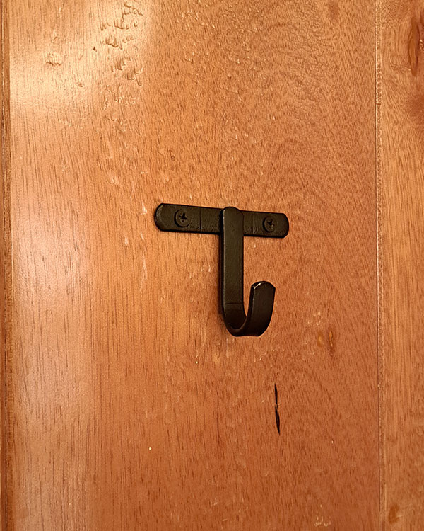 A single hook made of metal, oxide, screwed to a door. Found on a restaurant in Mexico City, Mexico, 2025.