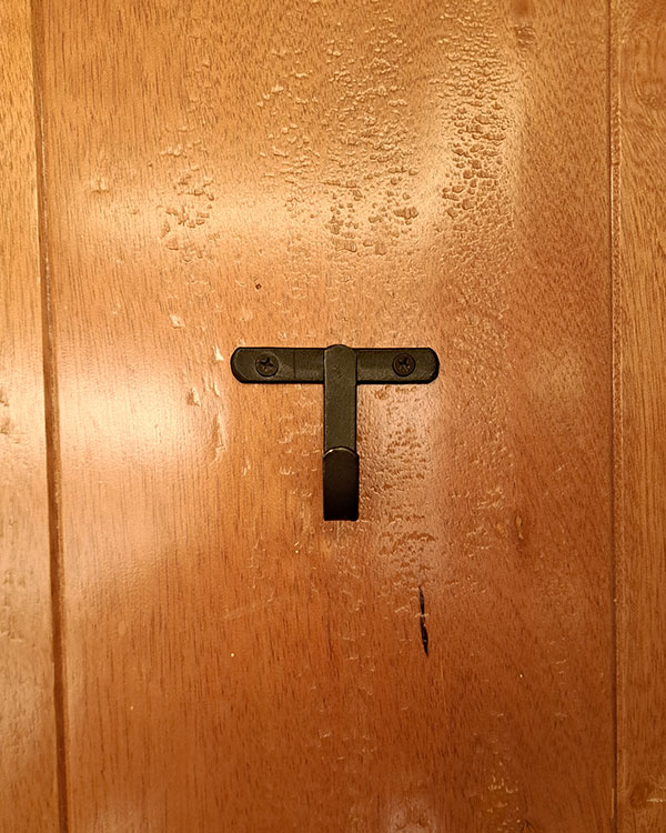 A single hook made of metal, oxide, screwed to a door. Found on a restaurant in Mexico City, Mexico, 2025.