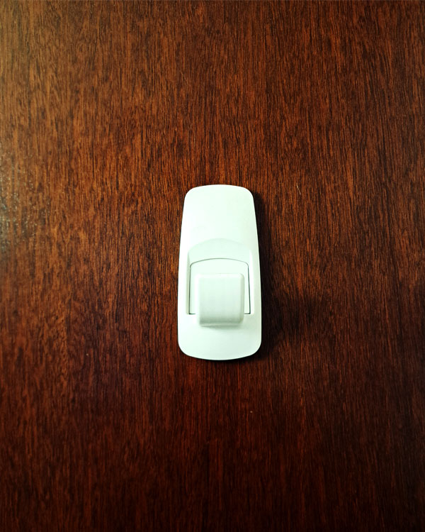 A single hook made of white plastic, glued to a door. Found on a home in Mexico City, Mexico, 2025.