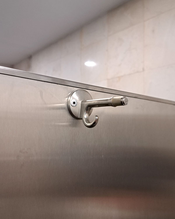 A double hook made of metal, nickel, riveted to a door. Found on an airport in Puerto Escondido, Mexico, 2026.