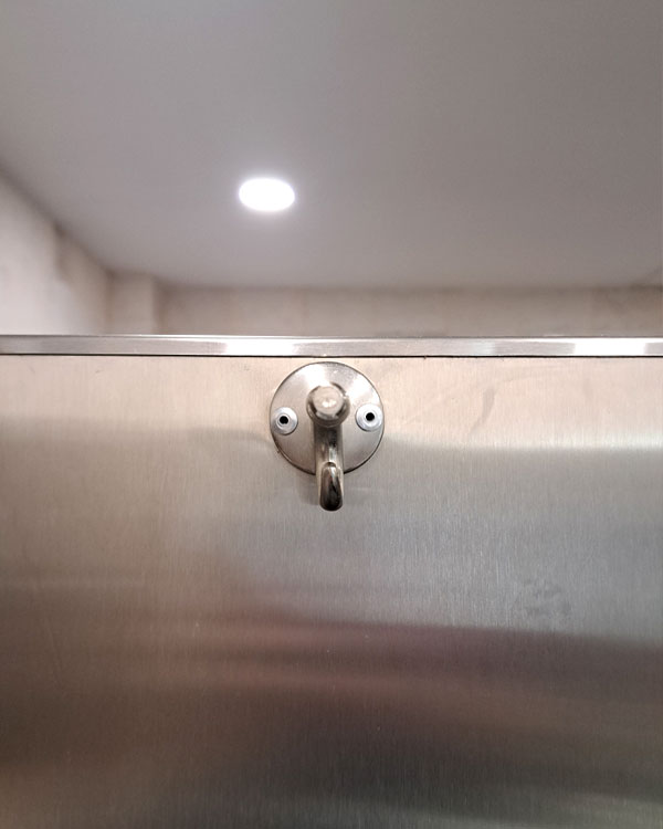 A double hook made of metal, nickel, riveted to a door. Found on an airport in Puerto Escondido, Mexico, 2026.
