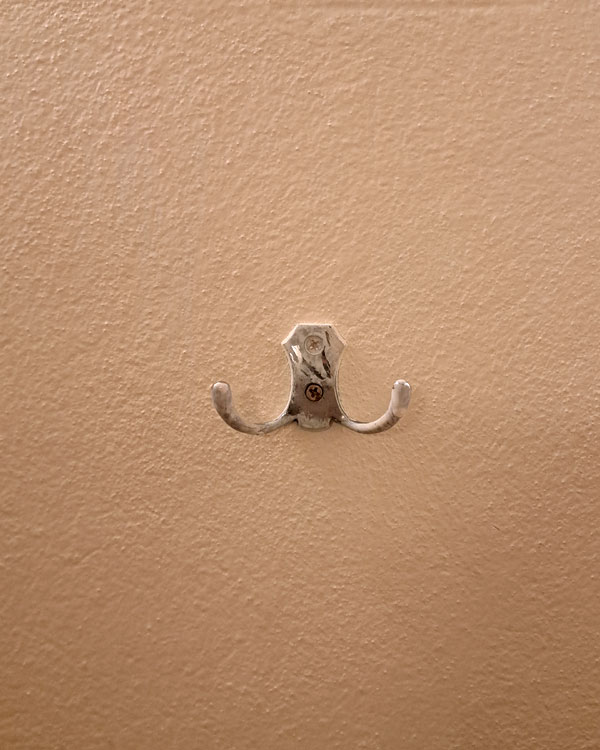 A double hook made of metal, chrome, screwed to a wall. Found on a restaurant in Mexico City, Mexico, 2026.
