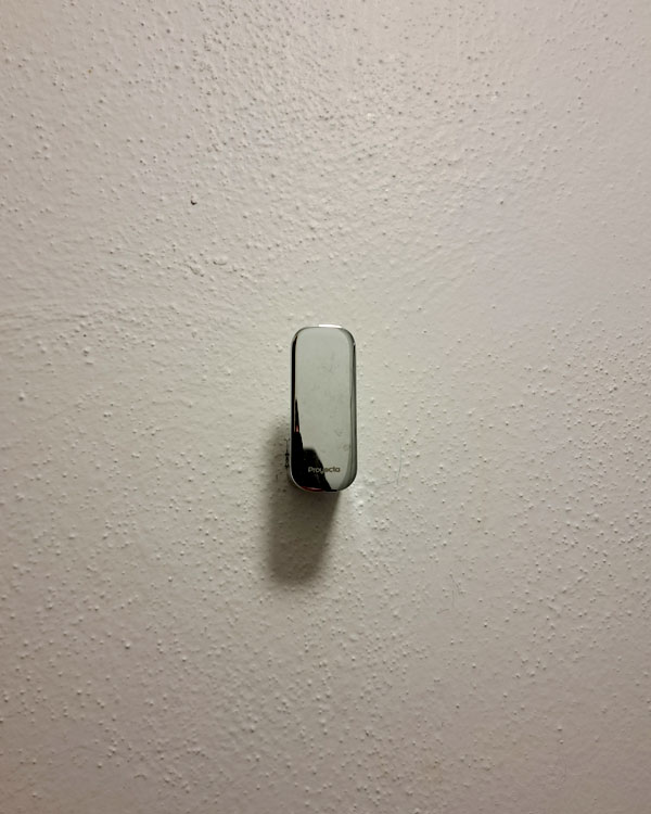 A single hook made of metal, chrome, fixed to a wall. Found on a home in Mexico City, Mexico, 2026.